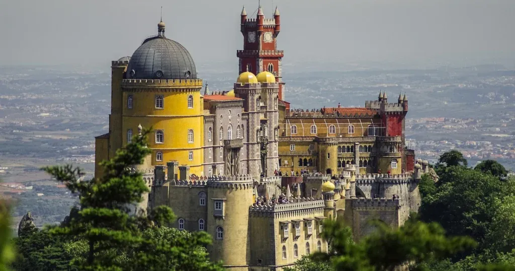 The colorful Pena Palace on a hilltop in Sintra, Portugal, symbolizing the historical charm of Spain and Portugal.