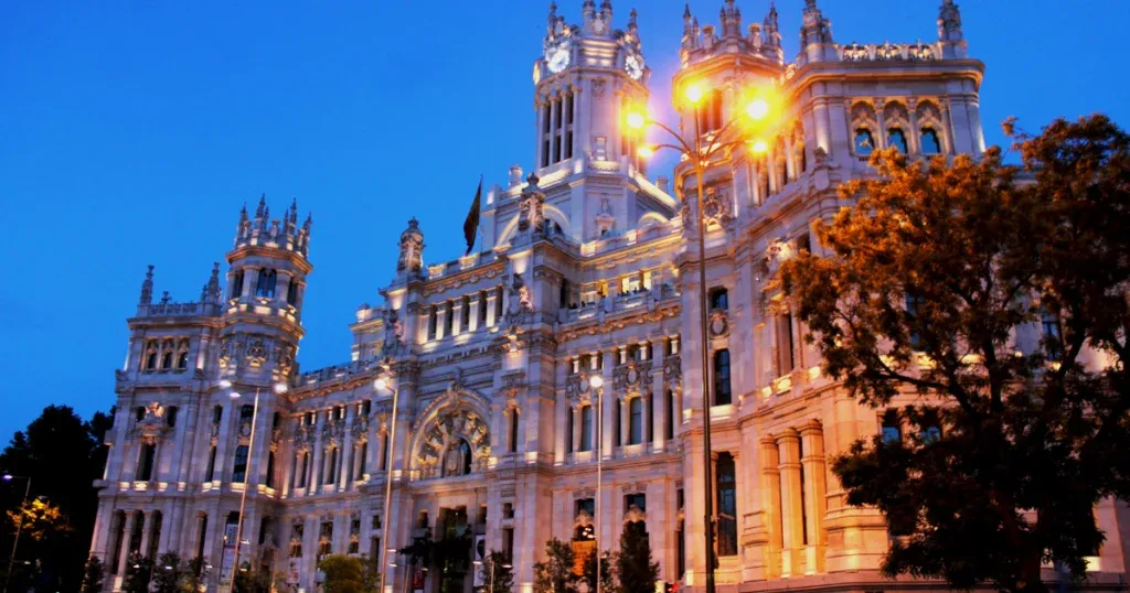 A stunning historic building illuminated at night in Madrid, representing the best place to stay in Madrid with its elegant and iconic charm.