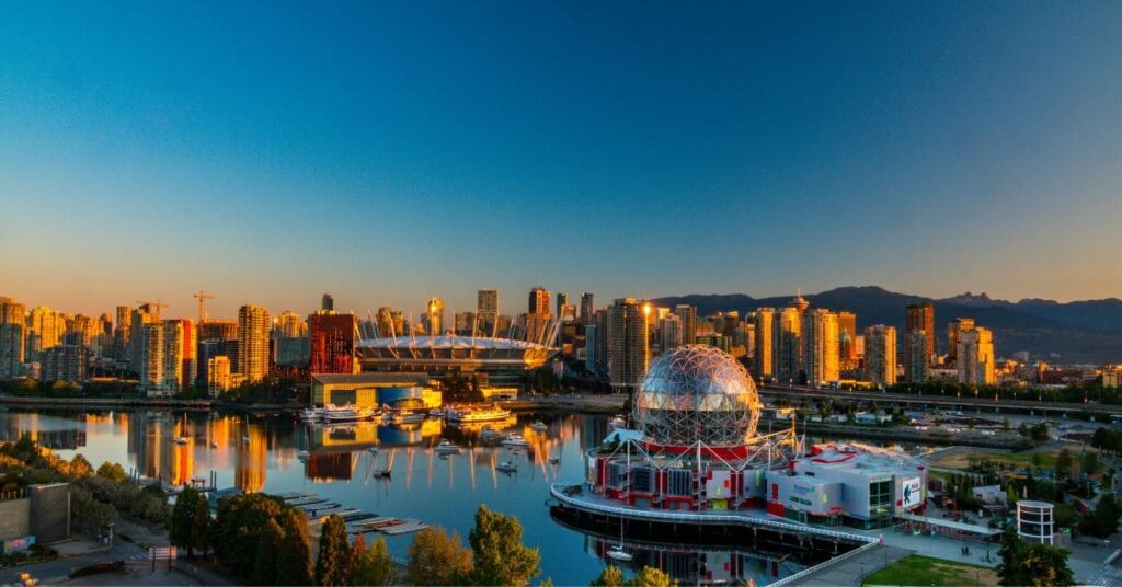 Scenic view of Vancouver skyline with waterfront, Science World, and mountains in the background during sunset