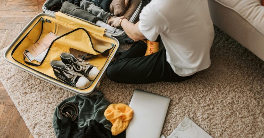 A traveler packing a suitcase with essential summer gear for travel Patagonia, including clothing, hiking boots, and accessories.