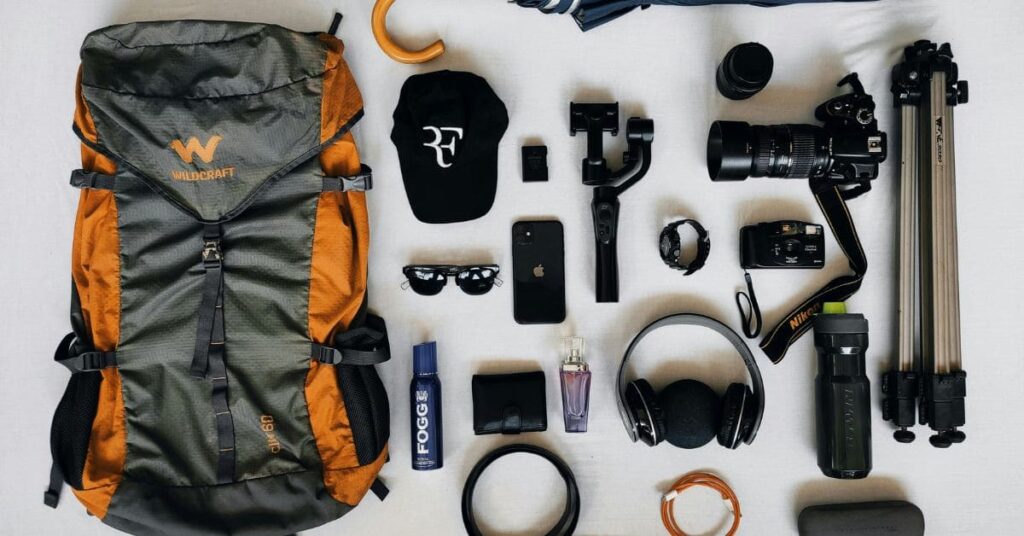 A neatly arranged flat lay of essential summer gear for travel Patagonia, including backpacks, hiking boots, waterproof jackets, and travel accessories.