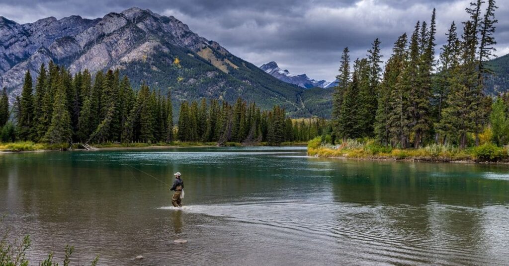 A breathtaking view of a serene landscape in a national park with rugged mountains, lush greenery, and a tranquil lake under a clear blue sky, showcasing one of the best places to visit in March in the USA.