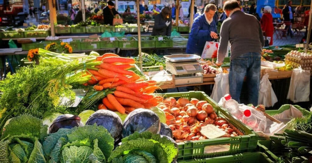 A bustling local market with vibrant stalls showcasing fresh produce, handmade goods, and lively crowds enjoying the atmosphere.