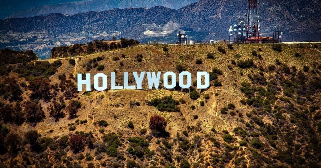 The iconic Hollywood sign perched on the hillside with a backdrop of rugged mountains and communication towers.