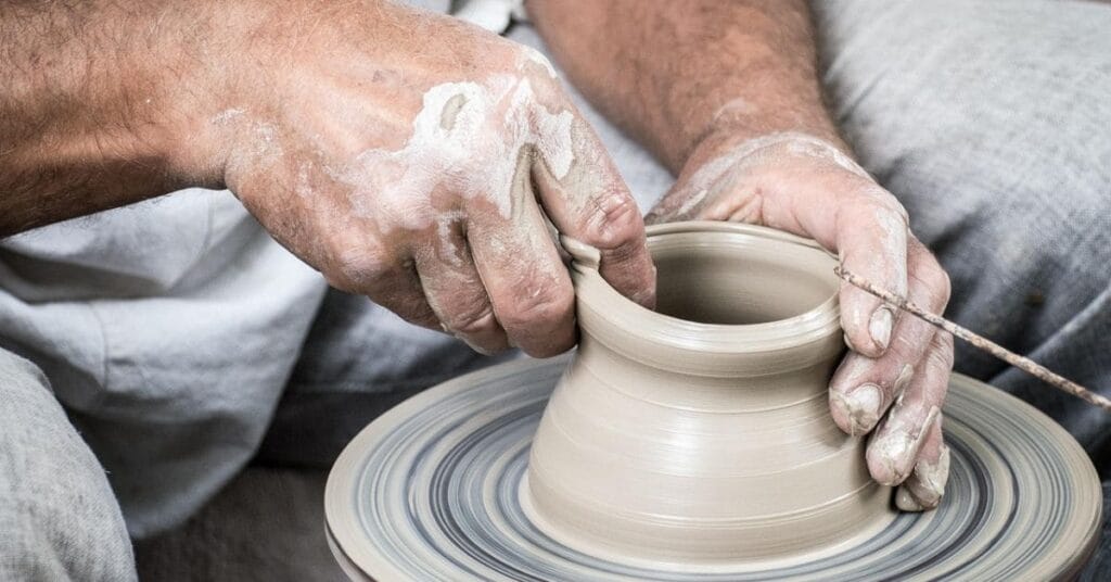 Hands of a potter shaping clay on a spinning pottery wheel, showcasing a hands-on creative activity.