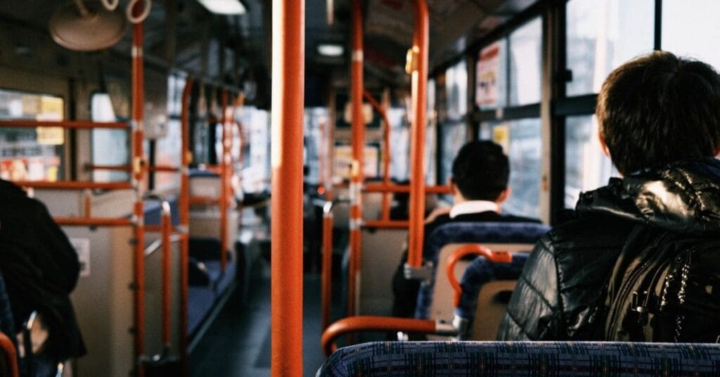  A view from inside a public bus with passengers seated, capturing the perspective of a commuter during travel.