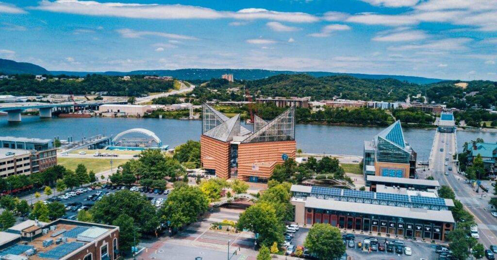 Aerial view of the Tennessee Aquarium in Chattanooga, with the city skyline and the Tennessee River in the background.