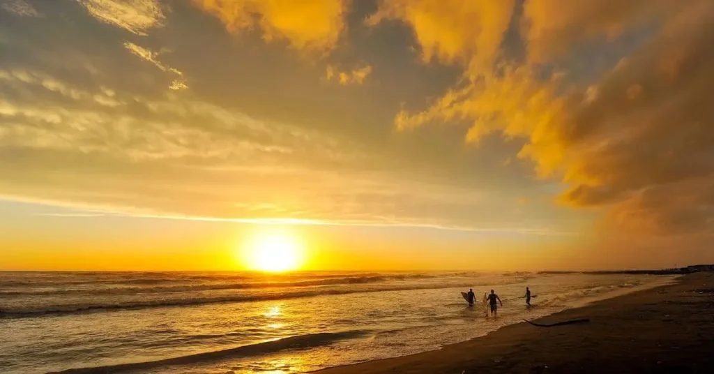 Sunbathers enjoying a beautiful sunset on a beach - one of the best places to travel in July.