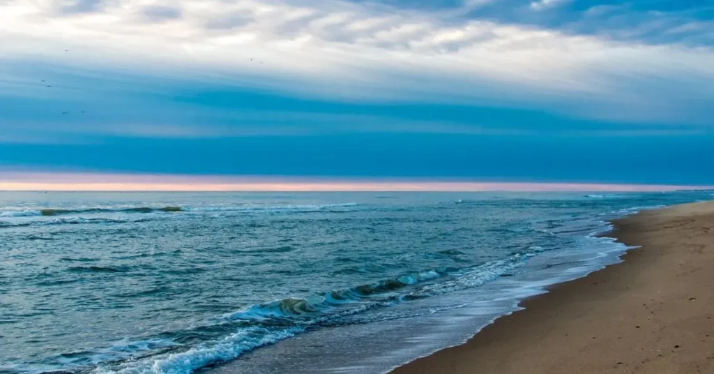 Serene beach scene with gentle waves lapping the shore under a vast blue sky - a reminder of the best places to travel in July.