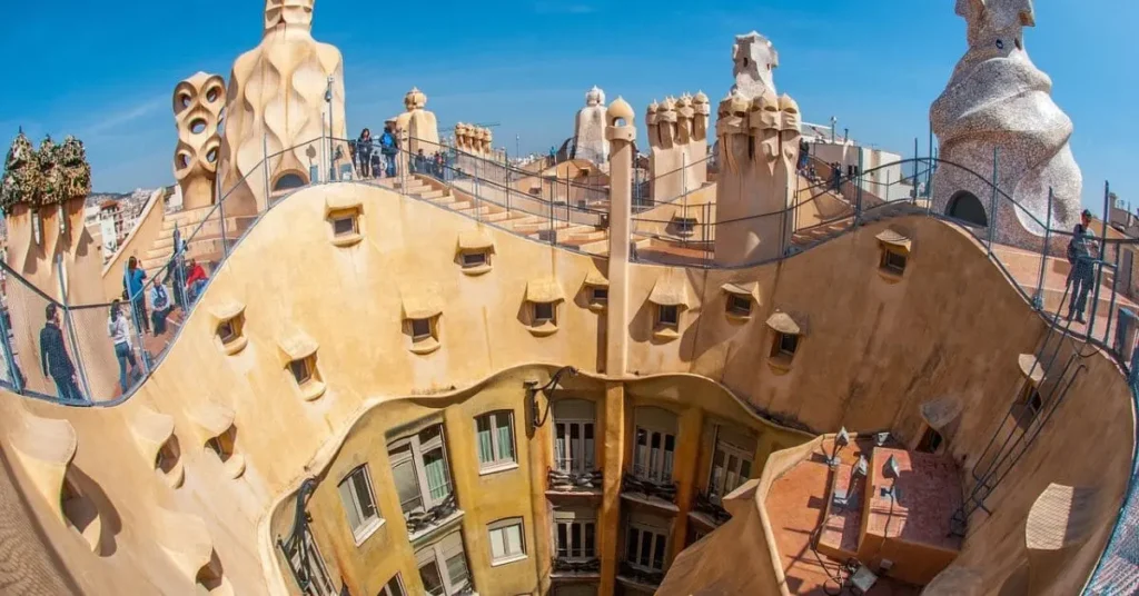 Rooftop view of Casa Milà in Barcelona, perfect for Portugal or Barcelona for travel as a Black girl, featuring Antoni Gaudí’s iconic architectural design under a clear blue sky.