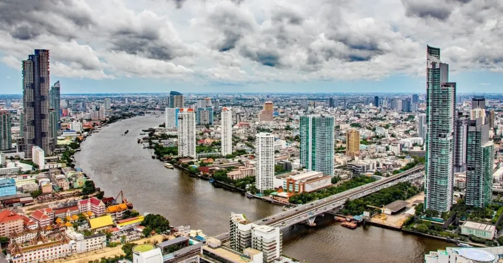 A breathtaking aerial view of Bangkok’s skyline, featuring modern skyscrapers, the Chao Phraya River, and bustling city life, showcasing the best time to visit Thailand.