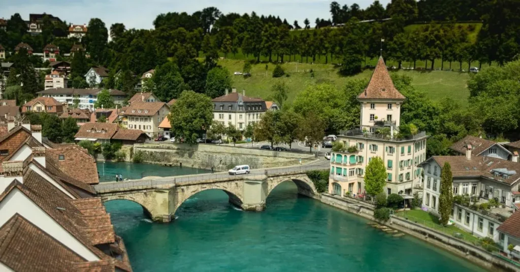 A picturesque view of Bern, Switzerland, featuring the turquoise Aare River, historic stone bridge, and charming medieval architecture—showcasing the beauty of the best time to travel to Switzerland.