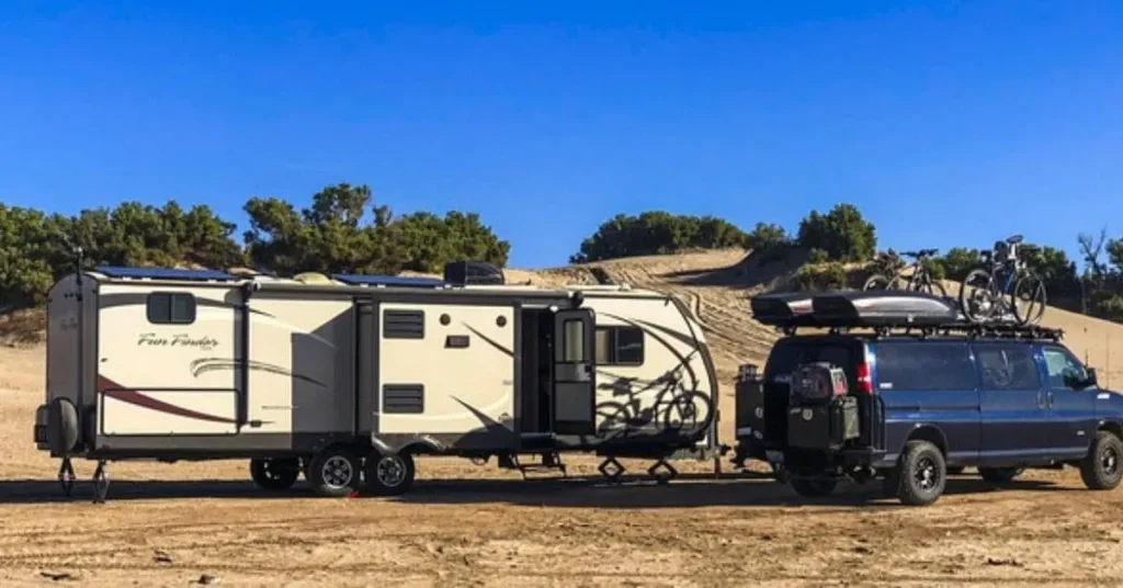 A Best Destination Travel Trailer parked in a scenic desert landscape, towed by a rugged van equipped with bicycles and outdoor gear, showcasing an ideal setup for adventure travel.