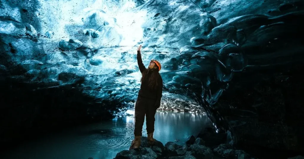 A traveler exploring a mesmerizing blue ice cave, one of the best places to travel to in February for a unique winter adventure.