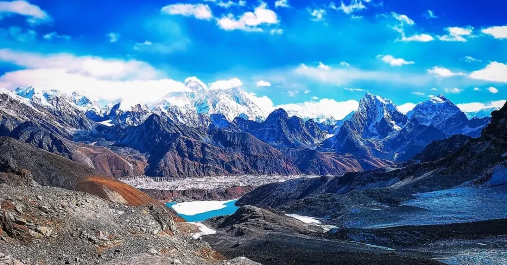 What is the best time to visit Mount Everest? This panoramic view showcases the stunning mountain range with Everest faintly visible among other peaks, highlighting the challenging yet beautiful landscape surrounding it.