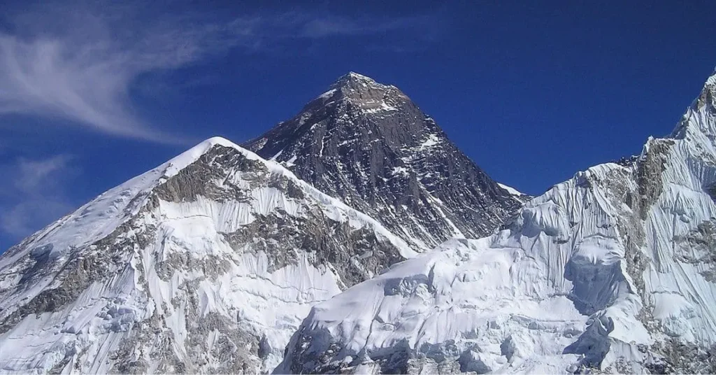 What is the best time to visit Mount Everest? This image shows the majestic peak under a bright blue sky, highlighting its snow-capped summit and challenging terrain.