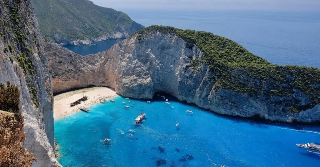 A stunning aerial view of Navagio Beach (Shipwreck Beach) in Zakynthos, Greece, showcasing its turquoise waters, white sandy beach, and the iconic shipwreck. This destination is often considered one of the cheap places to travel for a beautiful beach vacation.