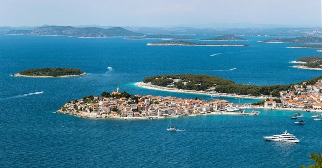 A scenic aerial view of a charming coastal town on a small island surrounded by crystal-clear blue waters and other islands, making it one of the best destinations to visit in September with its idyllic weather and tranquil atmosphere.