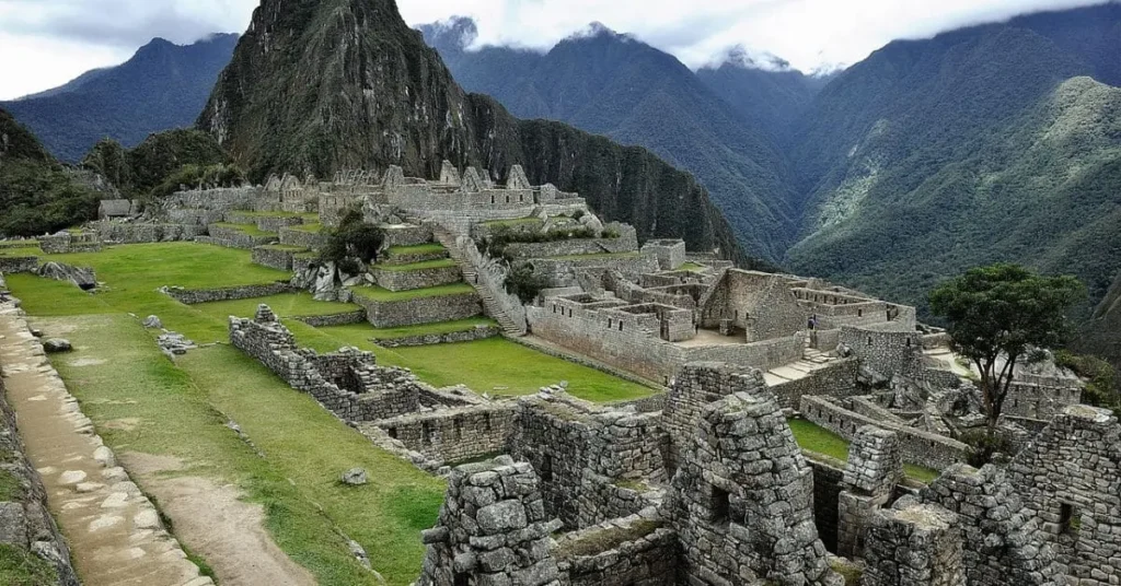 Ancient ruins of Machu Picchu, one of the top places to visit in Peru, surrounded by lush green mountains and misty clouds.