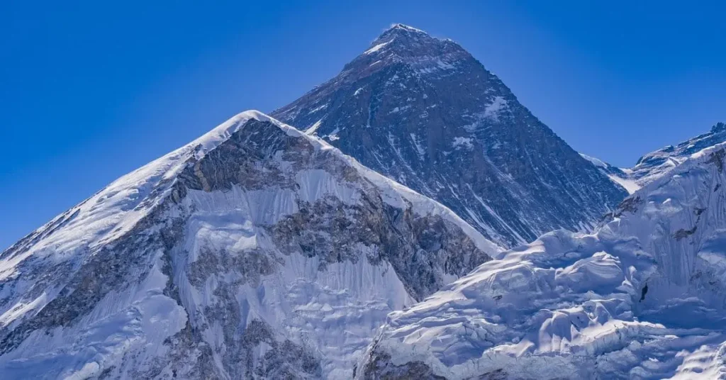 A close-up view of the majestic Mount Everest, showcasing its snow-covered peak and rugged terrain, illustrating two reasons to visit Mount Everest: for its breathtaking natural beauty and the ultimate mountaineering challenge.