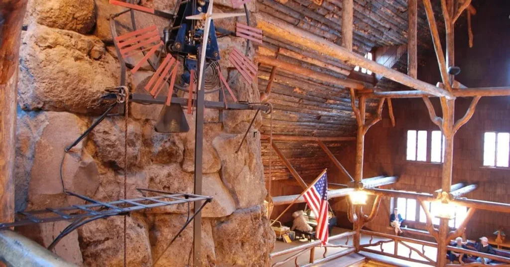 The rustic interior of the Old Faithful Inn in Yellowstone National Park, featuring a large stone fireplace, a historic clock, and wooden architecture—an iconic lodging option for those researching where to stay when visiting Yellowstone.