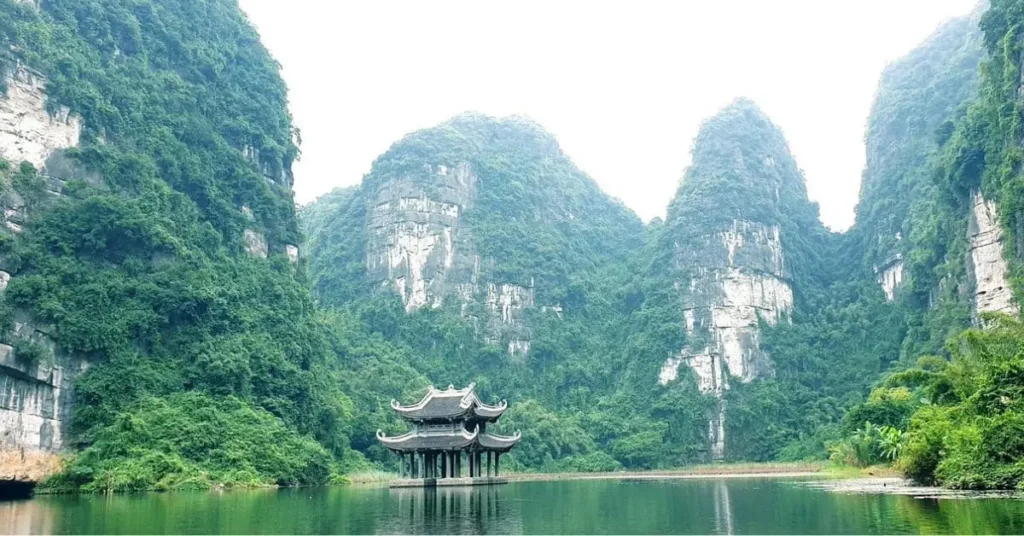 Scenic view of Trang An in Vietnam, one of the best Asian countries to visit, featuring a traditional floating temple surrounded by lush limestone mountains.